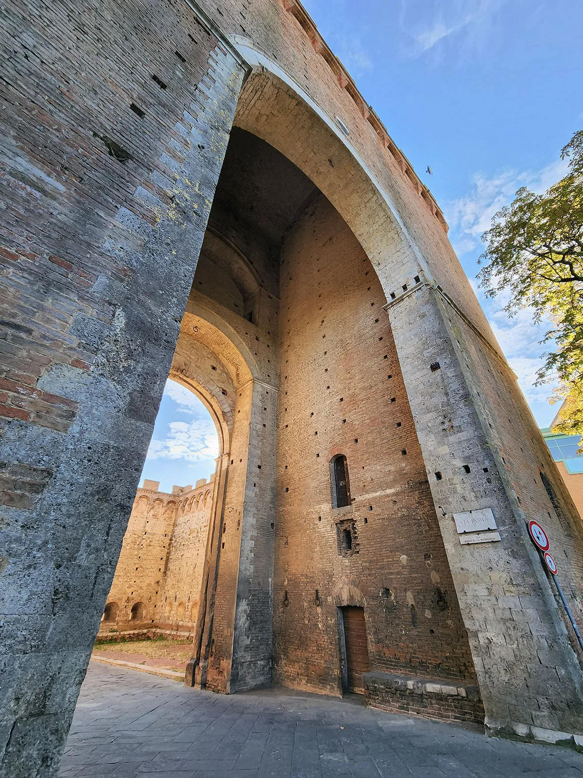 Portal medieval em tijolo e pedra — entrada fortificada nas muralhas de Siena